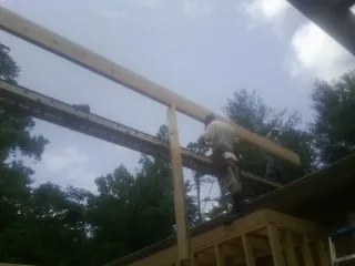 Carpenter setting a ridge beam over a new addition frame — Ice Dam Removal by Roofing Brothers in Tilden