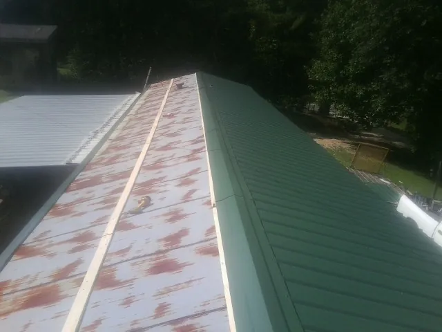 Old rusted panels beside newly installed green metal roofing — Wind Damage Roof Repair by Roofing Brothers in Tilden