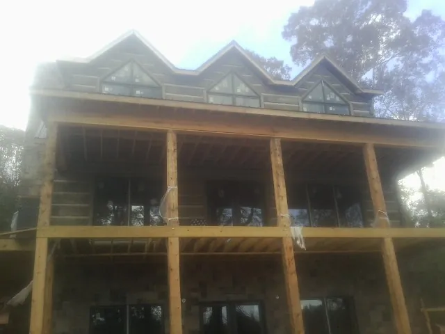 Dormers and porch framing on a large log home under construction — Roof Coating work by our crew in Tilden