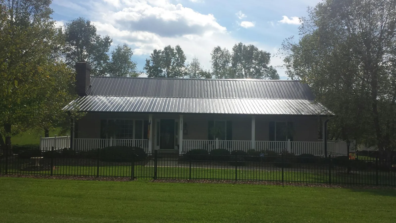 Gray metal roof on a brick ranch with a full width front porch — Gutter Guard Installation work by our crew in Tilden